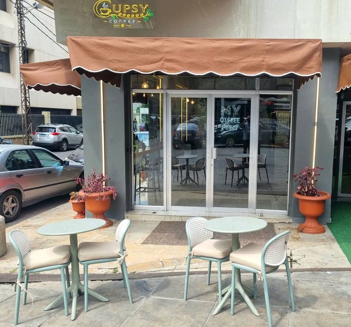 Cupsy Coffee outdoor seating with mint chairs under the brown awning in Dora